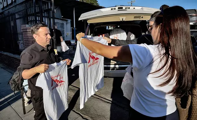 A movie fan sizes up Tee shirts during a merchandise Pop-Up event for the movie Anora on Saturday, Nov. 9, 2024 in Los Angeles. (AP Photo/Richard Vogel)