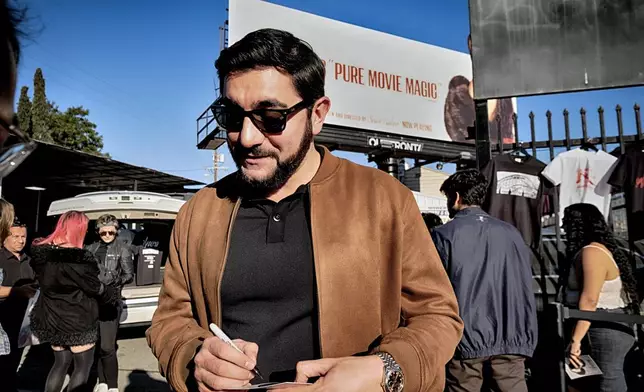 Actor Vache Tovmasyan signs an autograph for a fans during a merchandise Pop-Up event for the newly released film, Anora on Saturday, Nov. 9, 2024 in Los Angeles. (AP Photo/Richard Vogel)