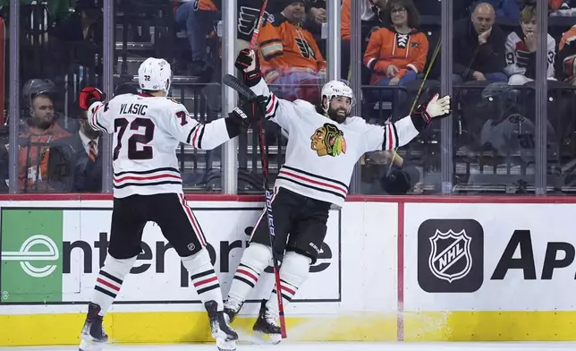 Chicago Blackhawks' Patrick Maroon, right, and Alex Vlasic celebrate after Maroon's goal during the second period of an NHL hockey game against the Philadelphia Flyers, Saturday, Nov. 23, 2024, in Philadelphia. (AP Photo/Matt Slocum)