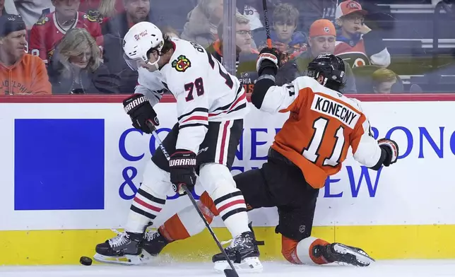 Chicago Blackhawks' TJ Brodie, left, and Philadelphia Flyers' Travis Konecny battle for the puck during the second period of an NHL hockey game, Saturday, Nov. 23, 2024, in Philadelphia. (AP Photo/Matt Slocum)