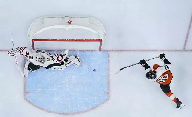 Philadelphia Flyers' Matvei Michkov, right, scores the game-winning goal past Chicago Blackhawks' Petr Mrazek during overtime in an NHL hockey game, Saturday, Nov. 23, 2024, in Philadelphia. (AP Photo/Matt Slocum)