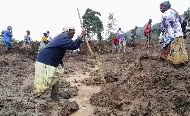 Rescue workers and people search for bodies after landslides following heavy rains buried 40 homes in the mountainous district of Bulambuli, eastern Uganda, Thursday, Nov. 28. 2024. (AP Photo/Jean Watala)