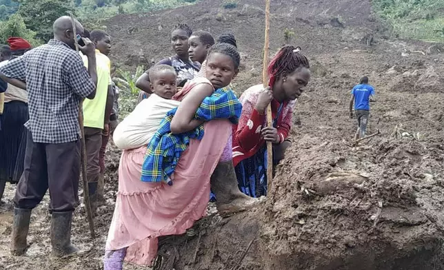 Rescue workers and people search for bodies after a landslide following heavy rains that buried 40 homes in the mountainous district of Bulambuli, eastern Uganda, Thursday, Nov. 28. 2024. (AP Photo/Jean Watala)