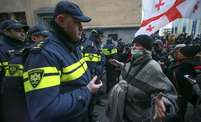 A woman gestures standing in front of police blocking the entrance of the Parliament's building during a rally to demand new parliamentary elections in the country, in Tbilisi, Georgia, Monday, Nov. 25, 2024. (AP Photo/Zurab Tsertsvadze)