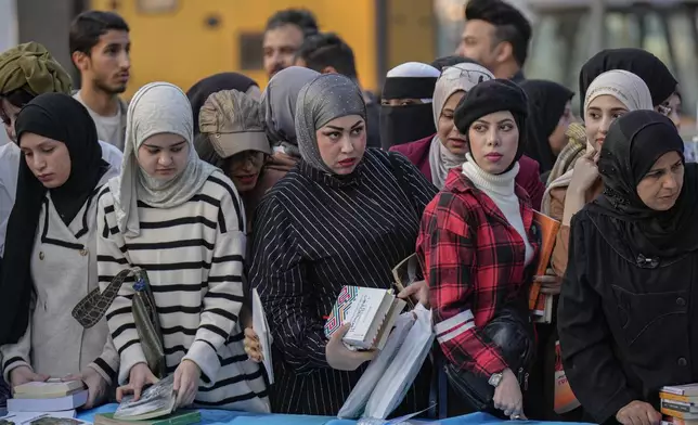 People browse through books displayed during the annual book festival in Abu Nawas street in central Baghdad, Iraq, Saturday, Nov.16, 2024. (AP Photo/Hadi Mizban)