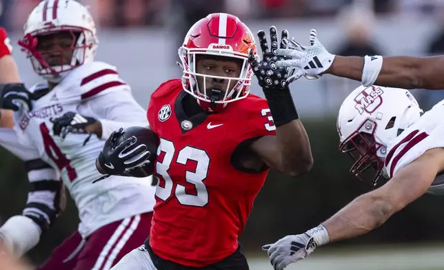 Georgia running back Chauncey Bowens (33) fends off UMass defenders as he runs the ball during the second half of an NCAA college football game, Saturday, Nov. 23, 2024, in Athens, Ga. (AP Photo/John Bazemore)