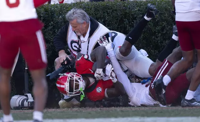 Georgia wide receiver Dominic Lovett (6) crashes into a sideline photographer after making a catch for a touchdown during the first half of an NCAA college football game against UMass, Saturday, Nov. 23, 2024, in Athens, Ga. (AP Photo/John Bazemore)