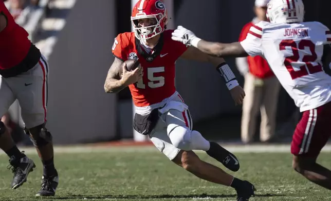 Georgia quarterback Carson Beck (15) looks for running room as UMass linebacker Gerrell Johnson (22) closes in during the first half of an NCAA college football game, Saturday, Nov. 23, 2024, in Athens, Ga. (AP Photo/John Bazemore)