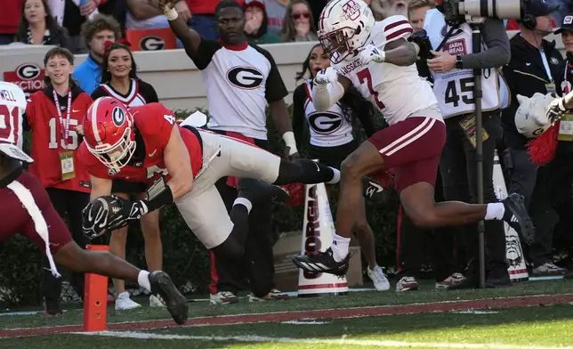 Georgia tight end Oscar Delp (4) dives in for aa touchdown after a catch as UMass defensive back Lake Ellis (7) gives chase during the first half of an NCAA college football game, Saturday, Nov. 23, 2024, in Athens, Ga. (AP Photo/John Bazemore)