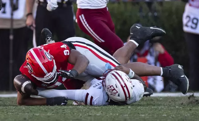 UMass quarterback AJ Hairston (8) fumbles as he is hit by Georgia defensive lineman Xzavier McLeod (94) during the second half of an NCAA college football game, Saturday, Nov. 23, 2024, in Athens, Ga. (AP Photo/John Bazemore)