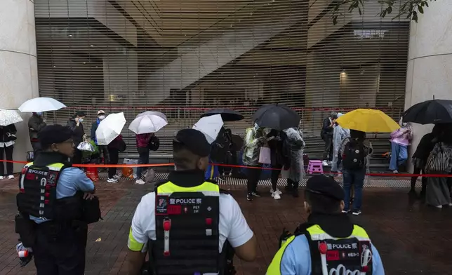 People wait outside the West Kowloon Magistrates' Courts in Hong Kong Tuesday, Nov. 19, 2024, ahead of the sentencing in national security case. (AP Photo/Chan Long Hei)