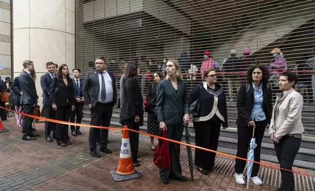 Representatives from various consulates wait in line outside the West Kowloon Magistrates' Courts in Hong Kong Tuesday, Nov. 19, 2024, ahead of the sentencing in national security case. (AP Photo/Chan Long Hei)