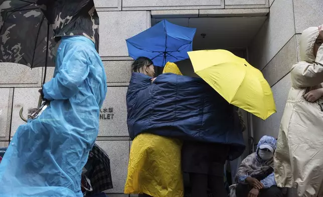 People wait outside the West Kowloon Magistrates' Courts in Hong Kong Tuesday, Nov. 19, 2024, ahead of the sentencing in national security case. (AP Photo/Chan Long Hei)