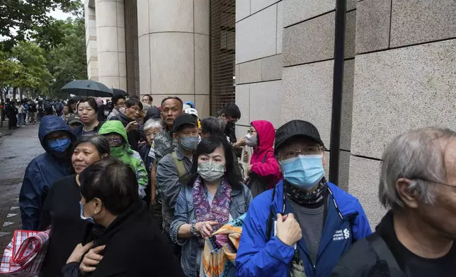 People wait outside the West Kowloon Magistrates' Courts in Hong Kong Tuesday, Nov. 19, 2024, ahead of the sentencing in national security case. (AP Photo/Chan Long Hei)