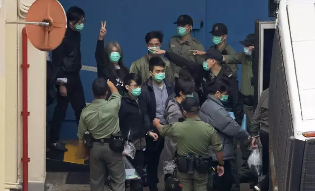 FILE - Former lawmaker Leung Kwok-hung, known as "Long Hair," second left, shows a victory sign as some of the 47 pro-democracy activists are escorted by Correctional Services officers to a prison van in Hong Kong, March 4, 2021. (AP Photo/Kin Cheung, File)