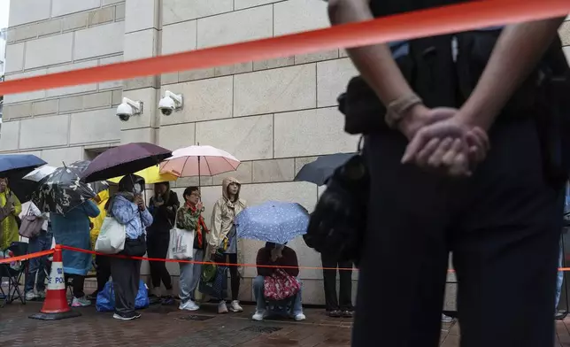 People wait outside the West Kowloon Magistrates' Courts in Hong Kong Tuesday, Nov. 19, 2024, ahead of the sentencing in national security case. (AP Photo/Chan Long Hei)