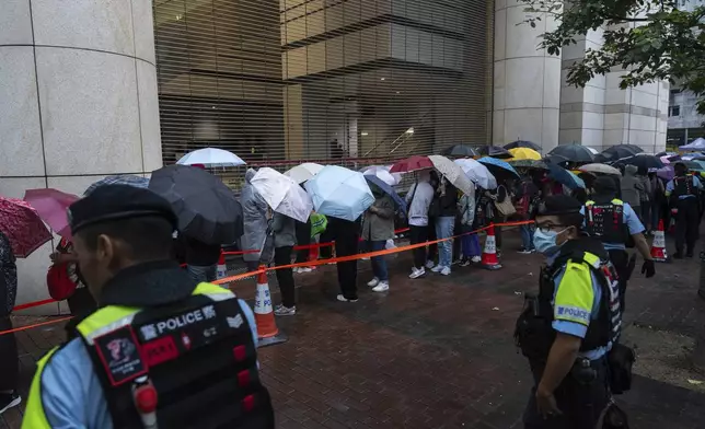 People wait outside the West Kowloon Magistrates' Courts in Hong Kong Tuesday, Nov. 19, 2024, ahead of the sentencing in national security case. (AP Photo/Chan Long Hei)