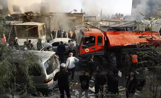 Firefighters and security officers gather at a destroyed building hit in an Israeli airstrike in Damascus, Syria, Thursday, Nov. 14, 2024. (AP Photo/Omar Sanadiki)