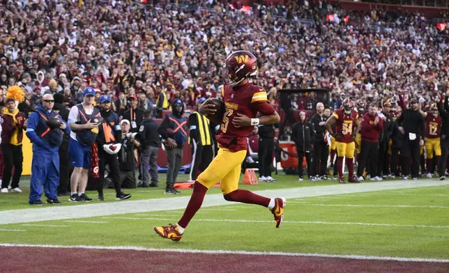 Washington Commanders quarterback Jayden Daniels (5) scores on a 2-point conversion attempt during the second half of an NFL football game against the Dallas Cowboys, Sunday, Nov. 24, 2024, in Landover, Md. (AP Photo/Nick Wass)