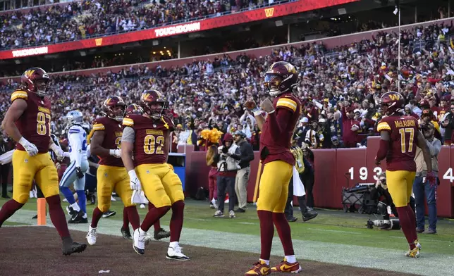 Washington Commanders quarterback Jayden Daniels (5), middle right, celebrates after running for a 17-yard touchdown during the second half of an NFL football game against the Dallas Cowboys, Sunday, Nov. 24, 2024, in Landover, Md. (AP Photo/Nick Wass)