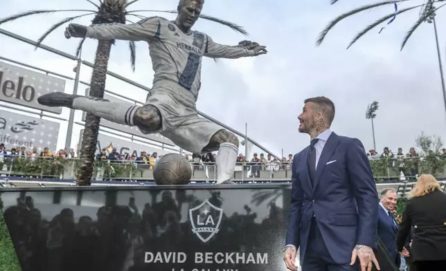 FILE - Former LA Galaxy MLS soccer midfielder David Beckham looks at a statue of himself at Legends Plaza in front of Dignity Health Sports Park in Carson, Calif., Saturday, March 2, 2019. (AP Photo/Ringo H.W. Chiu, File)