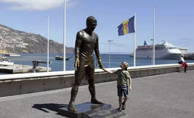 FILE - A child touches a statue of Portuguese star soccer player Cristiano Ronaldo in Funchal, the capital of Madeira island, Portugal, Monday, March 27 2017. (AP Photo/Armando Franca, File)