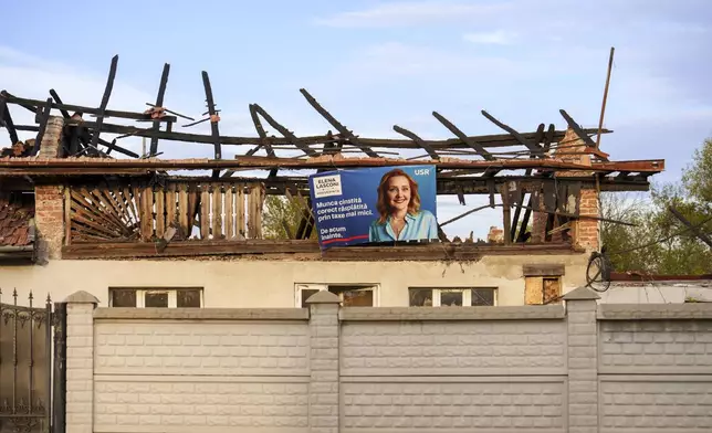 An electoral poster of Elena Lasconi, the Save Romania Union or USR, party candidate in the upcoming Nov. 24 presidential elections, is placed on a fire damaged building in Farcasesti Mosneni, Romania, Friday, Oct. 11, 2024. (AP Photo/Vadim Ghirda)