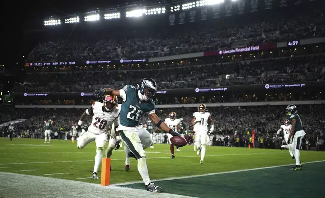 Philadelphia Eagles running back Saquon Barkley (26) scores past Washington Commanders safety Quan Martin (20) during the second half of an NFL football game against the Washington Commanders Thursday, Nov. 14, 2024, in Philadelphia. (AP Photo/Matt Slocum)