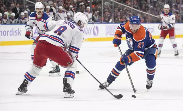 New York Rangers' Jacob Trouba (8) tries to defend against Edmonton Oilers' Connor McDavid (97) during second period NHL action in Edmonton on Saturday, November 23, 2024. (Jason Franson/The Canadian Press via AP)