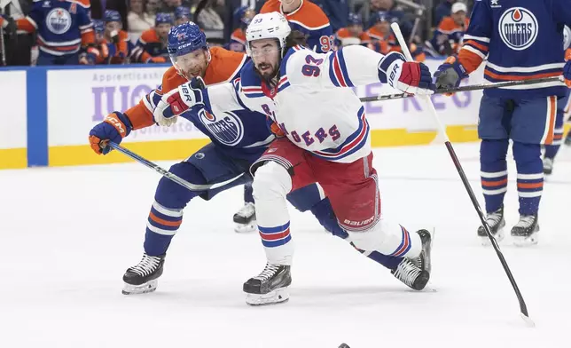 New York Rangers' Mika Zibanejad (93) and Edmonton Oilers' Brett Kulak (27) battle for the puck during first period NHL action in Edmonton on Saturday, November 23, 2024. (Jason Franson/The Canadian Press via AP)