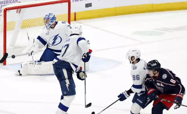 Columbus Blue Jackets defenseman Zach Werenski (8) scores the winning overtime goal past Tampa Bay Lightning goalie Jonas Johansson, left, defenseman Victor Hedman (77) and forward Nikita Kucherov (86) during an NHL hockey game in Columbus, Ohio, Thursday, Nov. 21, 2024. (AP Photo/Paul Vernon)