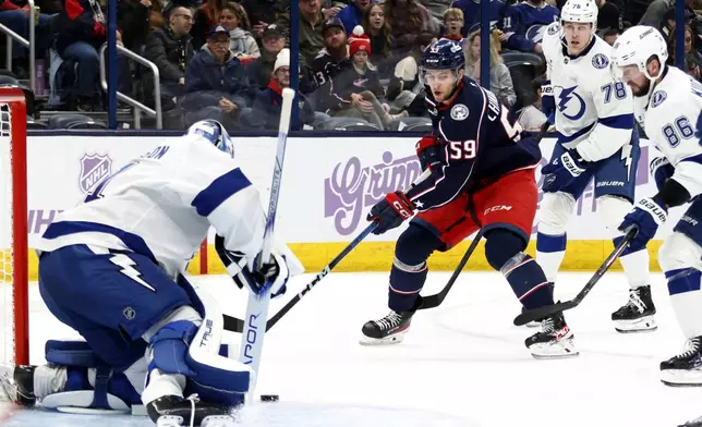 Columbus Blue Jackets forward Yegor Chinakhov (59) shoots the puck from between Tampa Bay Lightning goalie Jonas Johansson, left, defenseman Emil Martinsen Lilleberg (78) and forward Nikita Kucherov (86) during the second period of an NHL hockey game in Columbus, Ohio, Thursday, Nov. 21, 2024. (AP Photo/Paul Vernon)