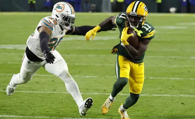 Green Bay Packers wide receiver Jayden Reed (11) runs from Miami Dolphins linebacker Jordyn Brooks (20) during a 12-yard touchdown reception in the first half of an NFL football game Thursday, Nov. 28, 2024, in Green Bay, Wis. (AP Photo/Mike Roemer)