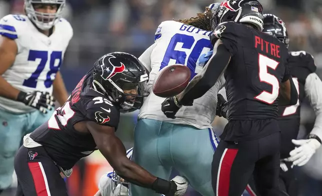 Houston Texans defensive end Dylan Horton, left, forces Dallas Cowboys offensive tackle Tyler Guyton, center, to fumble the ball during the second half of an NFL football game, Monday, Nov. 18, 2024, in Arlington, Texas. (AP Photo/Tony Gutierrez)