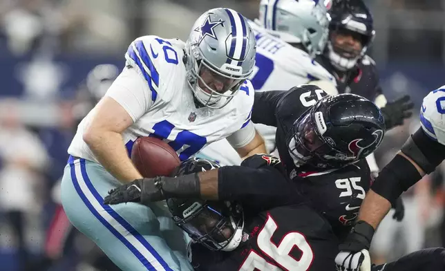 Dallas Cowboys quarterback Cooper Rush (10) tries to avoid being stopped by Houston Texans defensive end Denico Autry (96) and defensive end Derek Barnett (95) during the second half of an NFL football game, Monday, Nov. 18, 2024, in Arlington, Texas. (AP Photo/Tony Gutierrez)