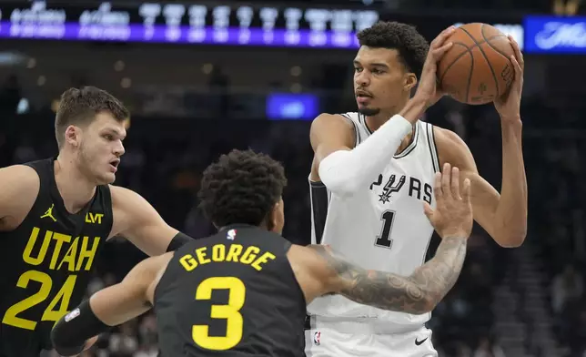 San Antonio Spurs center Victor Wembanyama (1) looks to pass as Utah Jazz center Walker Kessler (24) and guard Keyonte George (3) defend during the second half of an NBA basketball game, on Tuesday, Nov. 26, 2024, in Salt Lake City. (AP Photo/Bethany Baker)