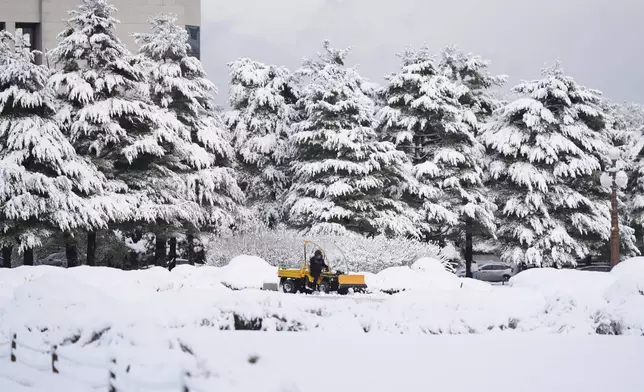 A worker uses a tractor to remove the snow at the National Assembly in Seoul, South Korea, Wednesday, Nov. 27, 2024. (AP Photo/Lee Jin-man)