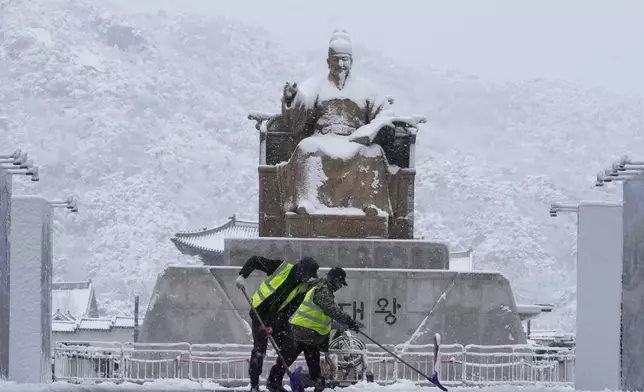 Workers clean snow in front of the statue of King Sejong at Gwanghwamun Square in Seoul, South Korea, Wednesday, Nov. 27, 2024. (AP Photo/Ahn Young-joon)