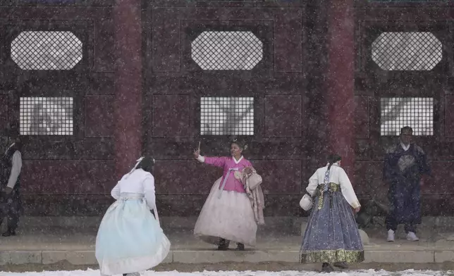 Visitors walk in snow at the Gyeongbok Palace, one of South Korea's well-known landmarks, in Seoul, South Korea, Wednesday, Nov. 27, 2024. (AP Photo/Lee Jin-man)