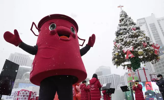 A volunteer man wearing a costume of a Salvation Army pot stands near a snow-covered Christmas tree in Seoul, South Korea, Wednesday, Nov. 27, 2024. (AP Photo/Ahn Young-joon)