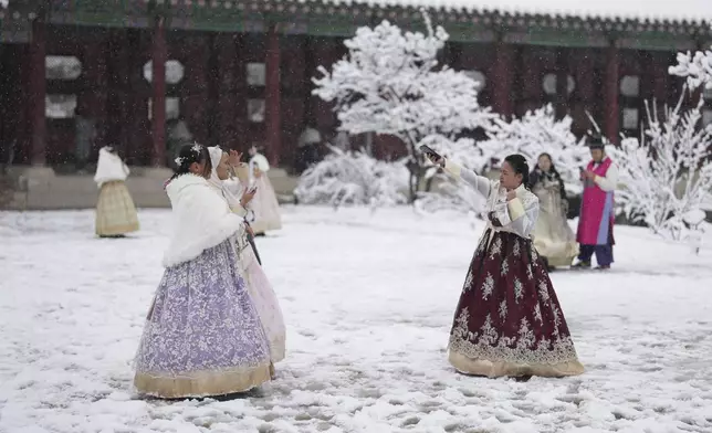 Mary Joy Morcisa from Philippines, right, gestures in snow at the Gyeongbok Palace, one of South Korea's well-known landmarks, in Seoul, South Korea, Wednesday, Nov. 27, 2024. (AP Photo/Lee Jin-man)