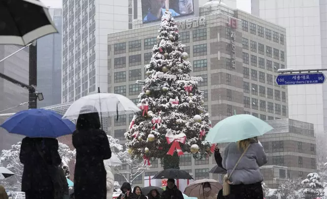 People pass by snow-covered a Christmas tree in Seoul, South Korea, Wednesday, Nov. 27, 2024. (AP Photo/Ahn Young-joon)