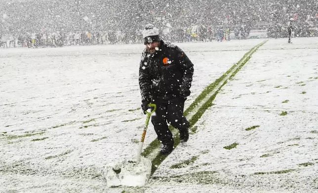 A groundskeeper shovels snow on the field in the second half of an NFL football game between the Cleveland Browns and the Pittsburgh Steelers, Thursday, Nov. 21, 2024, in Cleveland. (AP Photo/Sue Ogrocki)