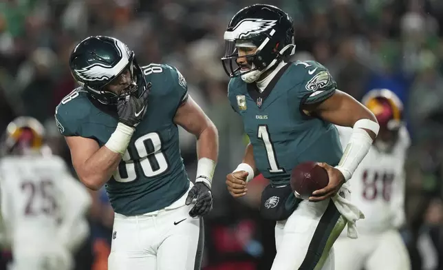 Philadelphia Eagles quarterback Jalen Hurts (1) is congratulated by teammate Dallas Goedert (88) after scoring during the second half of an NFL football game against the Washington Commanders Thursday, Nov. 14, 2024, in Philadelphia. (AP Photo/Matt Slocum)