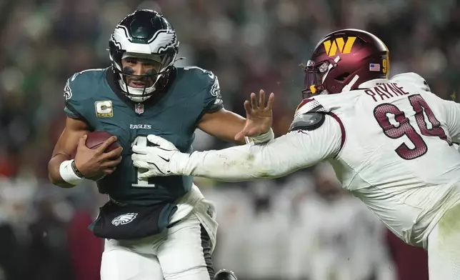 Philadelphia Eagles quarterback Jalen Hurts (1) runs as Washington Commanders defensive tackle Daron Payne (94) defends during the first half of an NFL football game Thursday, Nov. 14, 2024, in Philadelphia. (AP Photo/Matt Slocum)