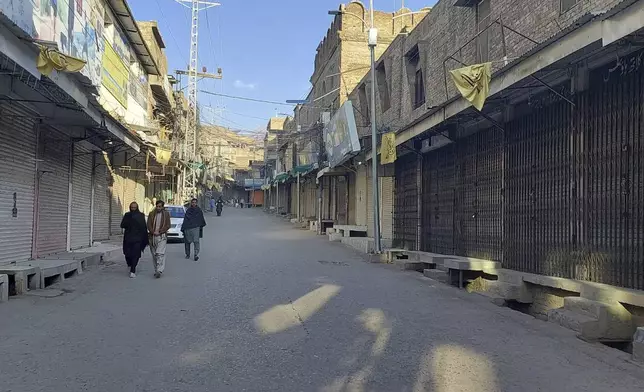 Local residents walk in a market, which closed due to strike called by traders as a protest against a gunmen firing incident, in Parachinar, main town of Kurram district of Pakistan's northwestern Khyber Pakhtunkhwa province, Friday, Nov. 22, 2024. (AP Photo/Hussain Ali)