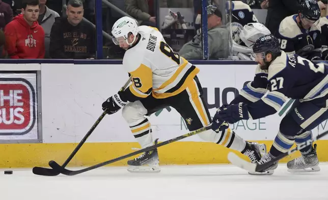 Pittsburgh Penguins forward Michael Bunting, left, chases the puck in front of Columbus Blue Jackets defenseman Zachary Aston-Reese during the first period of an NHL hockey game in Columbus, Ohio, Friday, Nov. 15, 2024. (AP Photo/Paul Vernon)