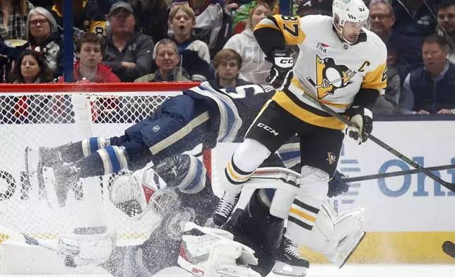 Pittsburgh Penguins forward Sidney Crosby, right, collides with Columbus Blue Jackets defenseman Gavin Bayreuther, center, and goalie Elvis Merzlikins during the second period of an NHL hockey game in Columbus, Ohio, Friday, Nov. 15, 2024. (AP Photo/Paul Vernon)