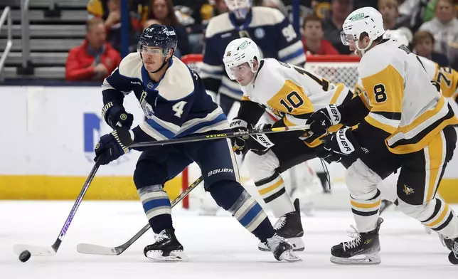 Columbus Blue Jackets forward Cole Sillinger, left, controls the puck in front of Pittsburgh Penguins forward Drew O'Connor, center, and forward Michael Bunting during the second period of an NHL hockey game in Columbus, Ohio, Friday, Nov. 15, 2024. (AP Photo/Paul Vernon)