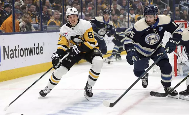 Pittsburgh Penguins forward Rickard Rakell, left, passes the puck in front of Columbus Blue Jackets defenseman Gavin Bayreuther during the first period of an NHL hockey game in Columbus, Ohio, Friday, Nov. 15, 2024. (AP Photo/Paul Vernon)